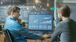 duas pessoas sentadas na frente de um computador com programas de power BI