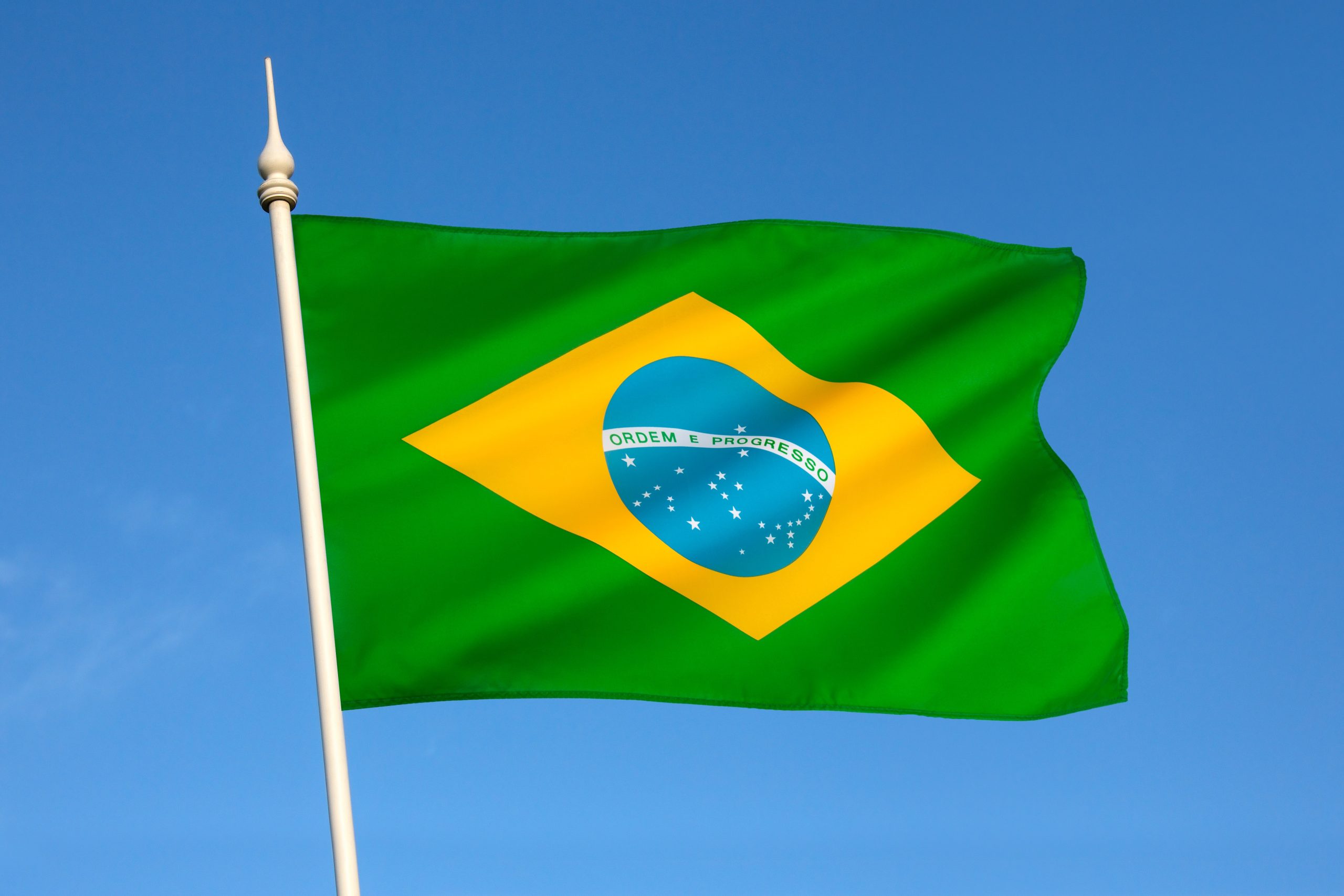 Bandeira do Brasil em um mastro e o céu azul de fundo