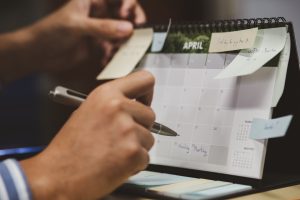 Mão de um homem organizando seu calendário mensal