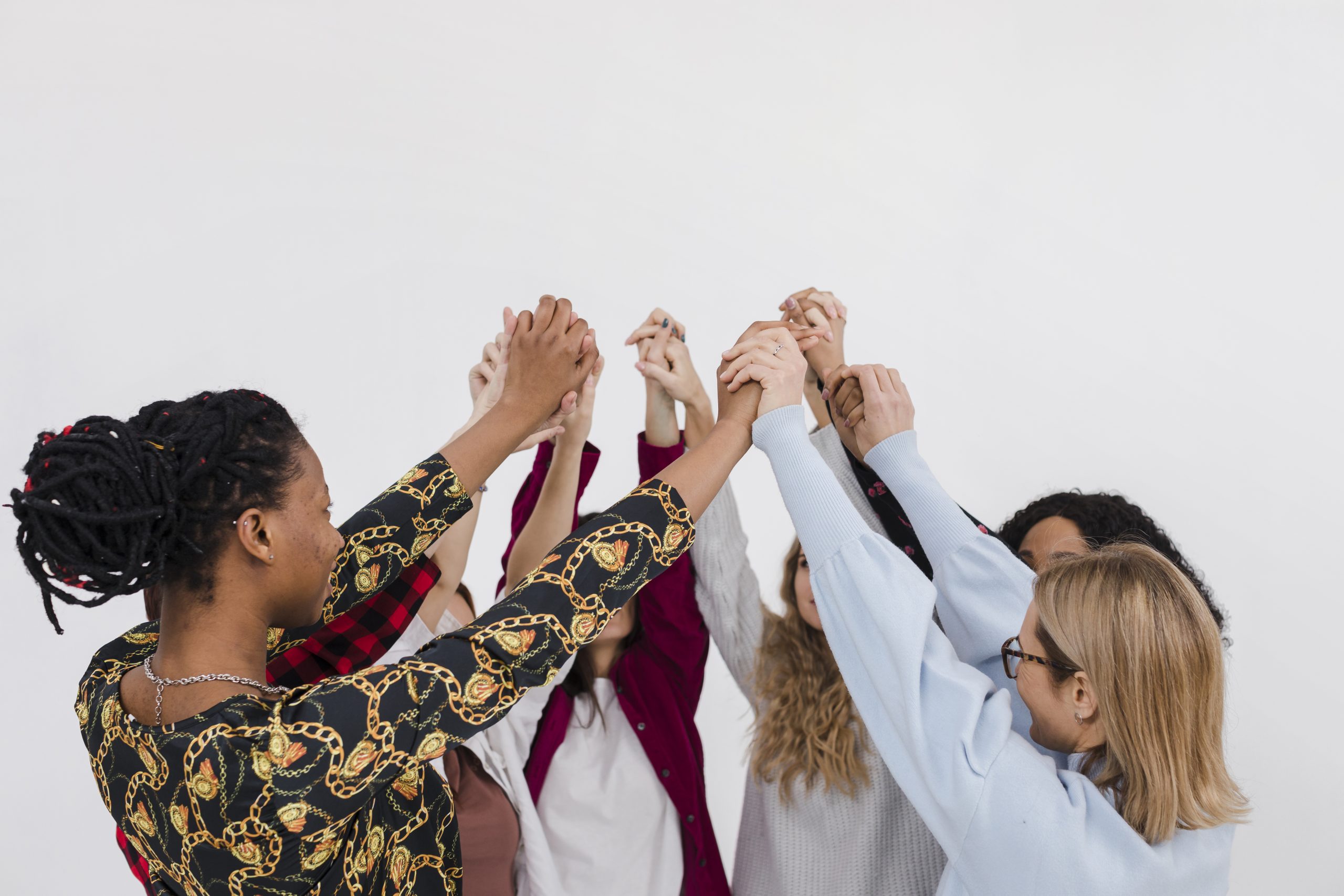 Cinco mulheres líderes dando as mãos no alto.