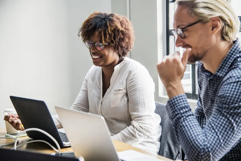 Uma mulher e um homem em reunião de trabalho com seus laptops abertos. Conceito: feedback construtivo