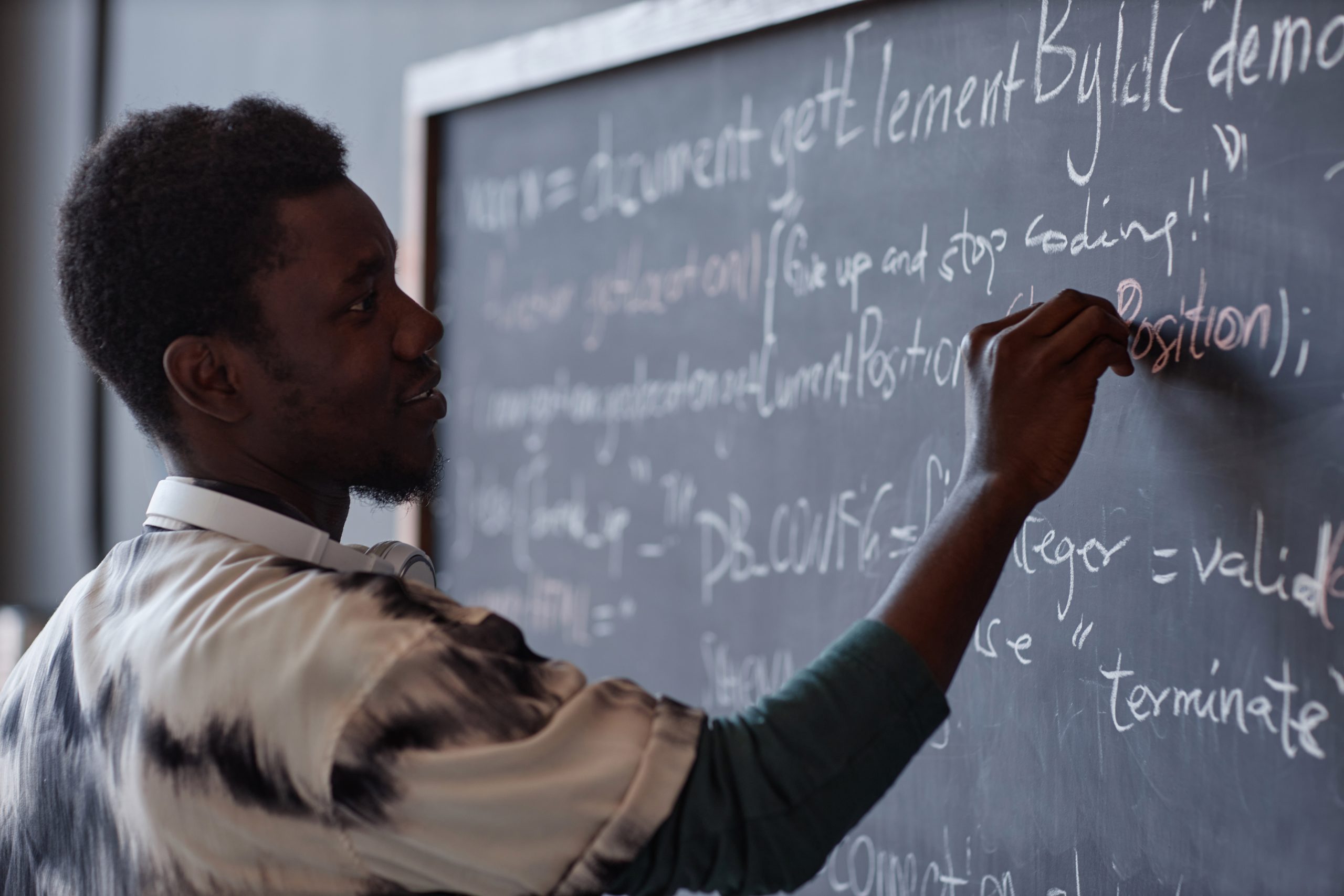 Professor negro escrevendo com giz em uma lousa 