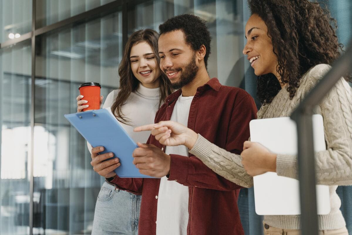 Reunião informal entre três pessoas, analisando um documento em pé