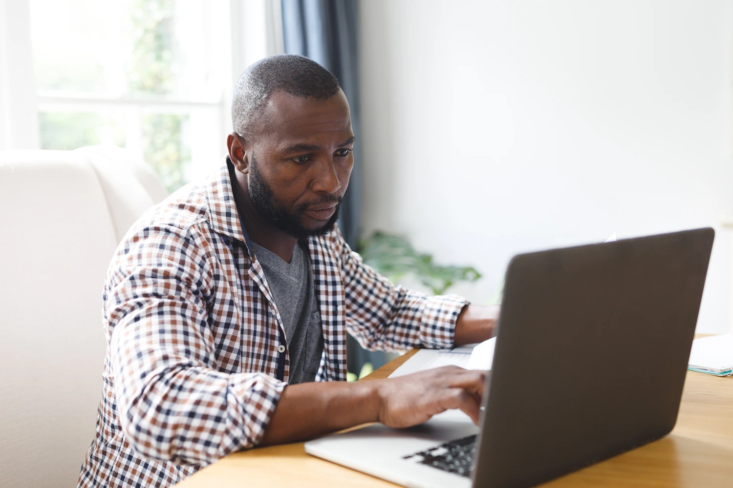 Homem negro trabalhando remotamente no seu laptop, mostrando o que é trabalho remoto.