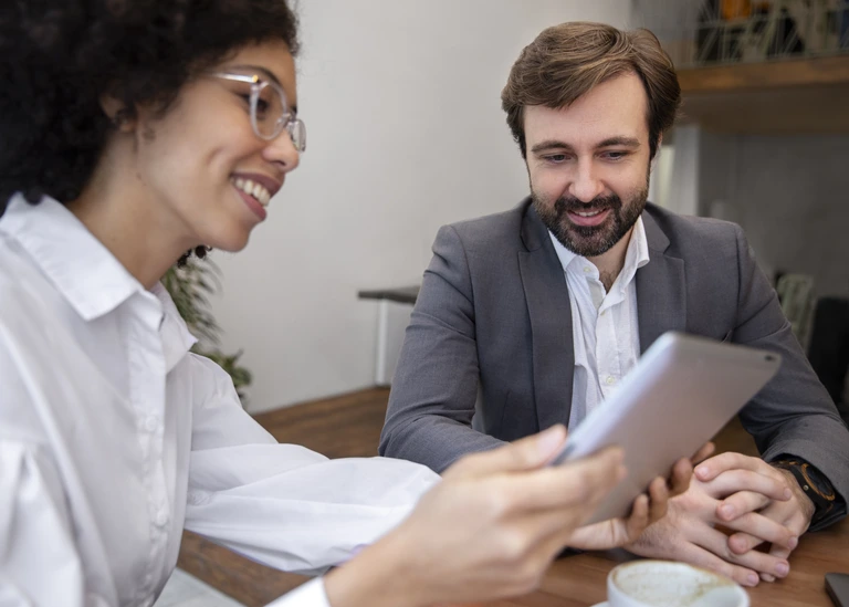 Uma líder de equipe segurando um tablet aplicando um tipo de feedback com uma pessoa de sua equipe