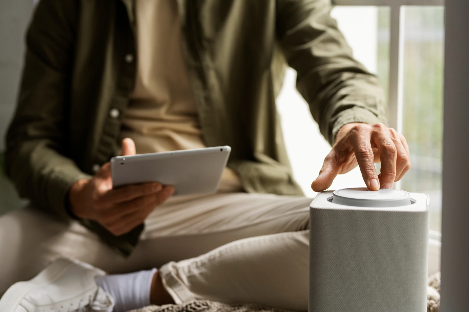 Homem utilizando um tablet e interagindo com um dispositivo inteligente, representando o uso da inteligência artificial na automação do dia a dia.