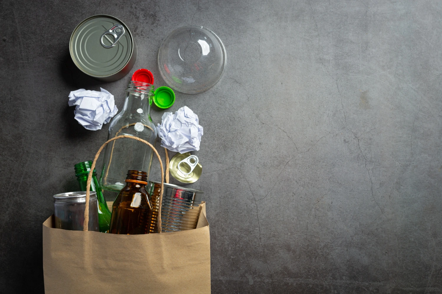 Uma sacola de papel e diversos itens recicláveis. Conceito: reciclagem e consumo consciente
