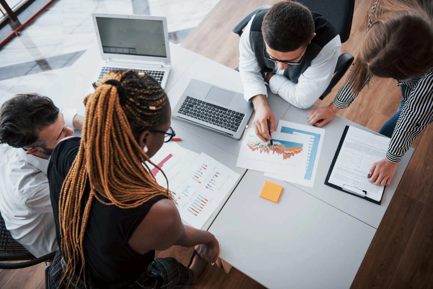 Equipe reunida analisando gráficos e estratégias em uma mesa de trabalho, simbolizando o desenvolvimento de equipes.