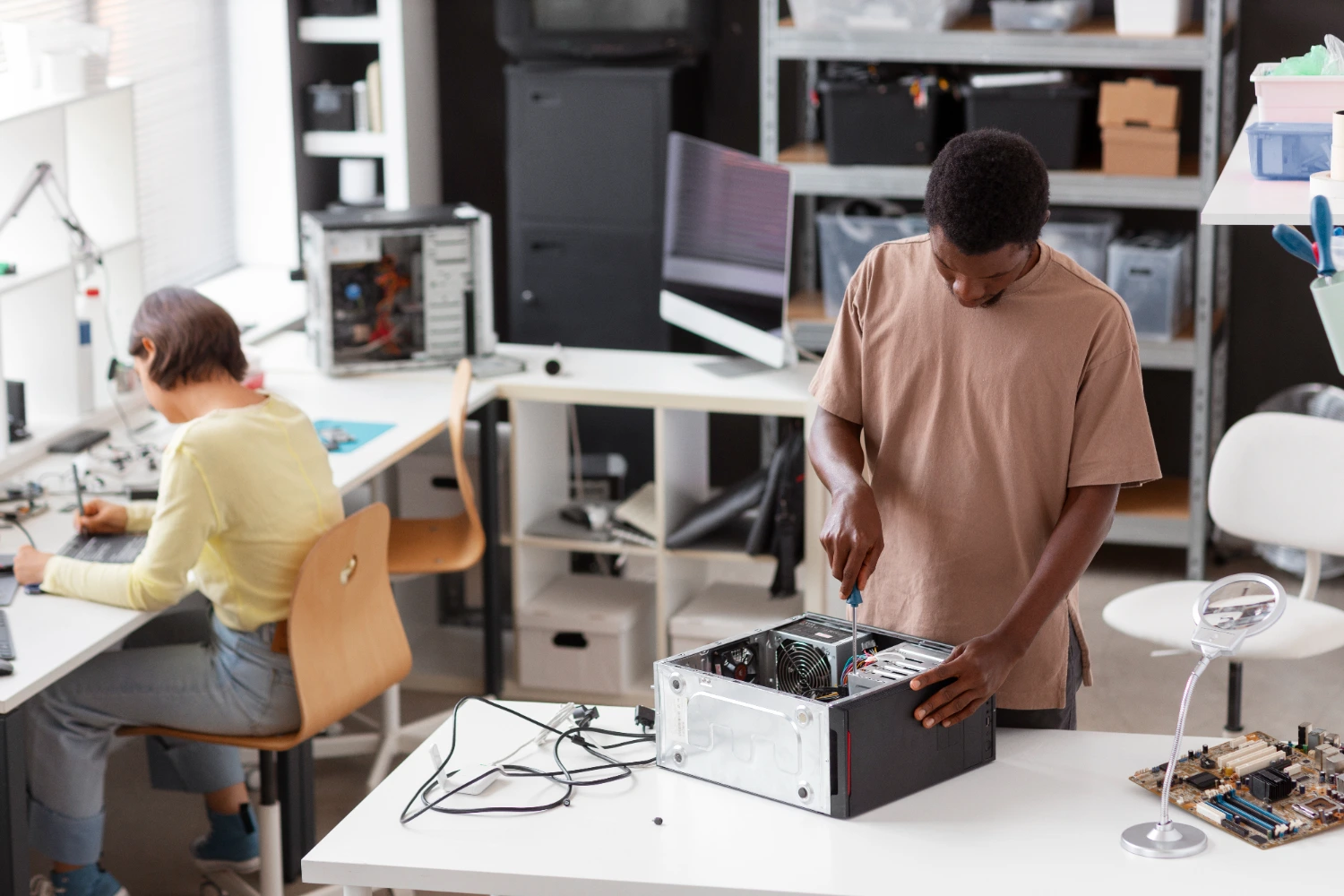  Jovem montando um computador em ambiente de laboratório, representando o aprendizado prático de noções de informática e hardware.