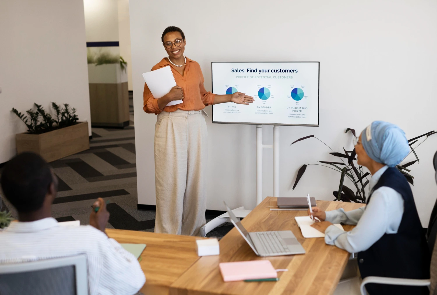 Imagem de uma profissional apresentando dados sobre clientes enquanto discute estratégias de carreira em ESG com seus colegas em uma reunião de trabalho.