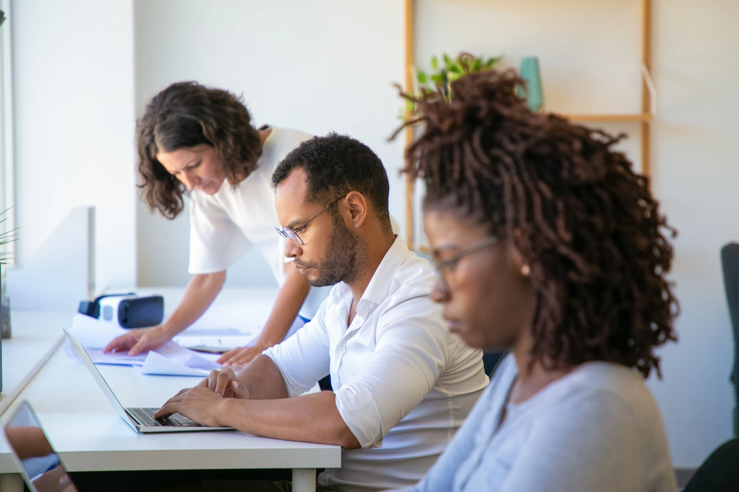Profissionais em um ambiente de trabalho focados em tarefas, com uma mesa de trabalho organizada, representando o desenvolvimento por meio de cursos livres.