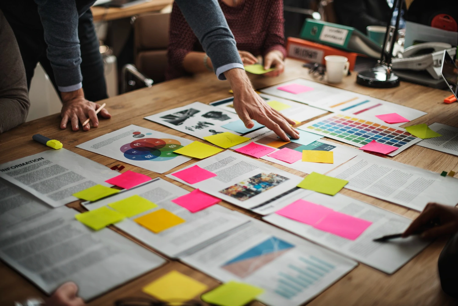 Equipe analisando documentos com gráficos e métricas de marketing, usando post-its coloridos para organizar informações.