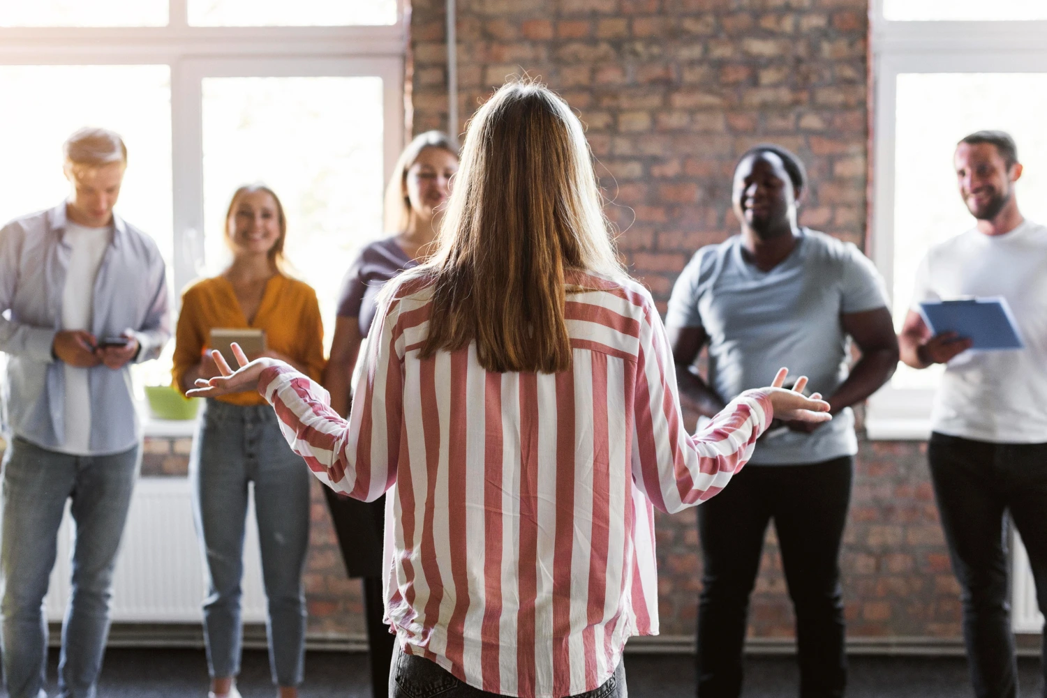 Mulher lidera reunião com equipe diversa, ilustrando diferentes tipos de liderança em ambientes corporativos colaborativos.