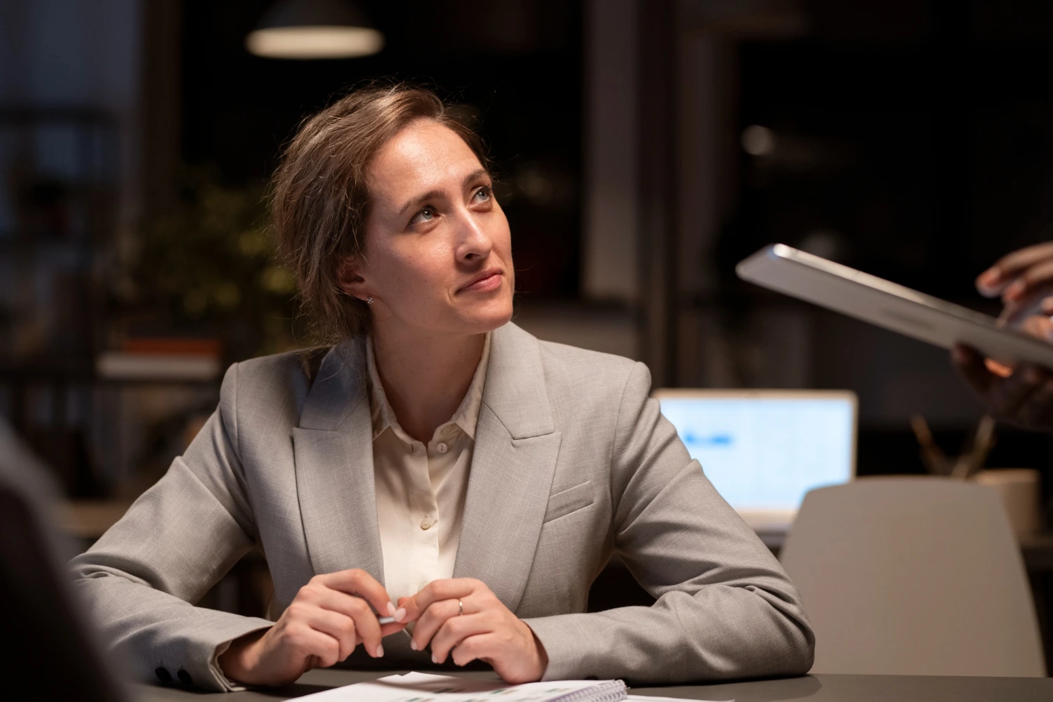 Mulher em traje de negócios olha para cima pensativa, focada em como se preparar para carreira executiva.