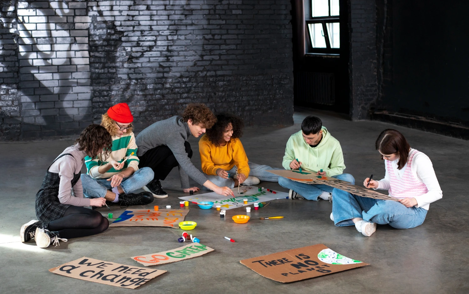 Grupo de jovens colaborando em atividade criativa com cartazes e tintas, representando a aplicação do design thinking na educação em atividades coletivas de inovação e solução de problemas.